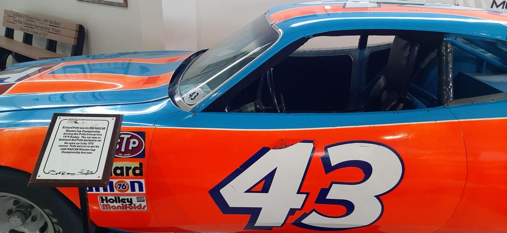 la Dodge Charger 1974 de Richard Petty vue de profil avec zoom sur l'habitacle (de l'extérieur) - livrée Blue Petty et orange, numéro 43