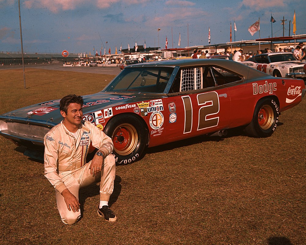 Bobby Allison accroupi devant une Dodge Charger