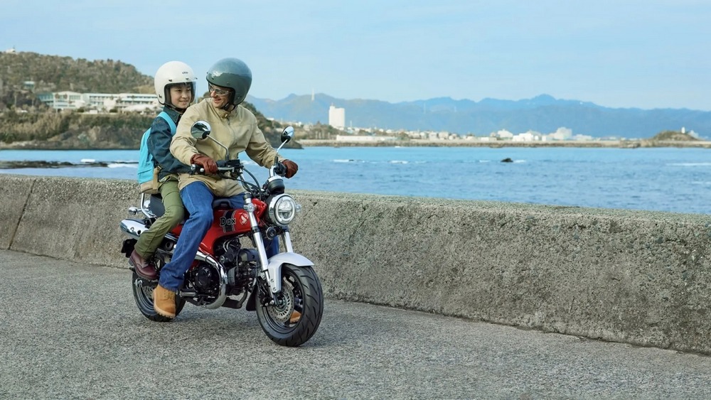 2 personnes sont sur un Honda Dax 125 rouge vu de 3/4 avant droit