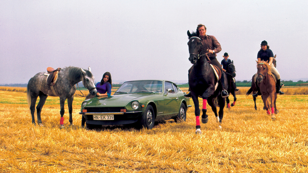 verte foncée vue de 3/4 avant gauche, dans un champs fauché, entourée de chevaux et de cavaliers