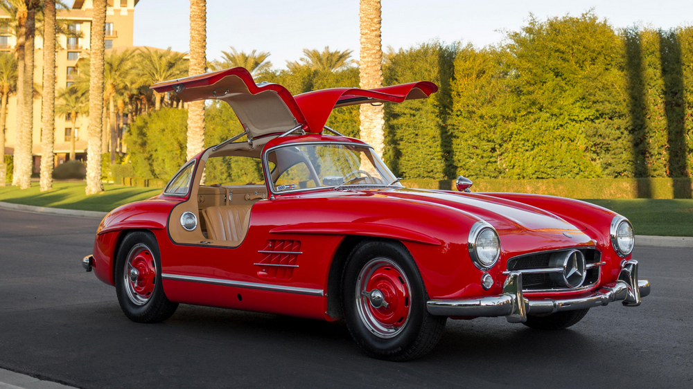 la Mercedes-Benz 300 SL 1955 rouge vue de 3/4 avant droit, intérieur beige, portières ouvertes