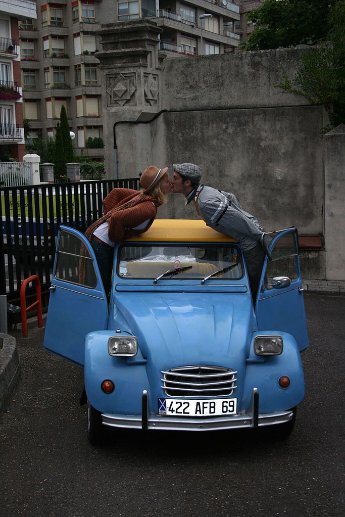 un couple s'embrasse au-dessus du toit d'une 2CV